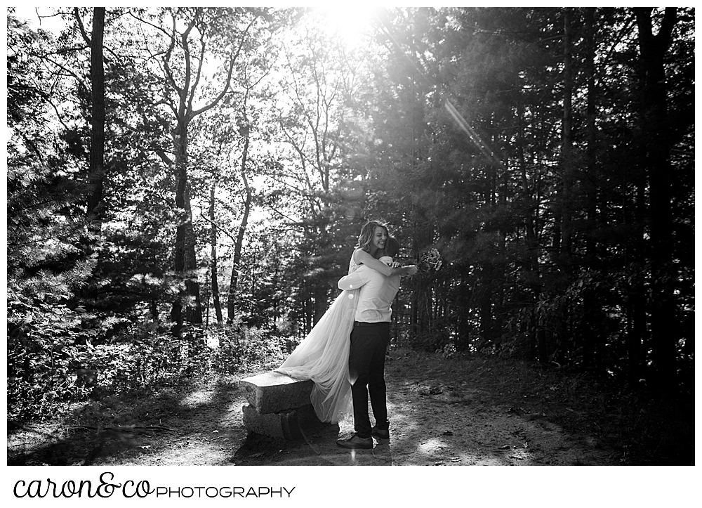 black and white photo of a bride on a bench, jumping into her groom's arms