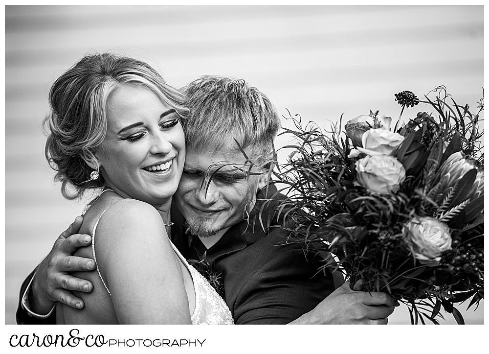 black and white photo of a bride and groom hugging after their Rangeley Maine wedding ceremony